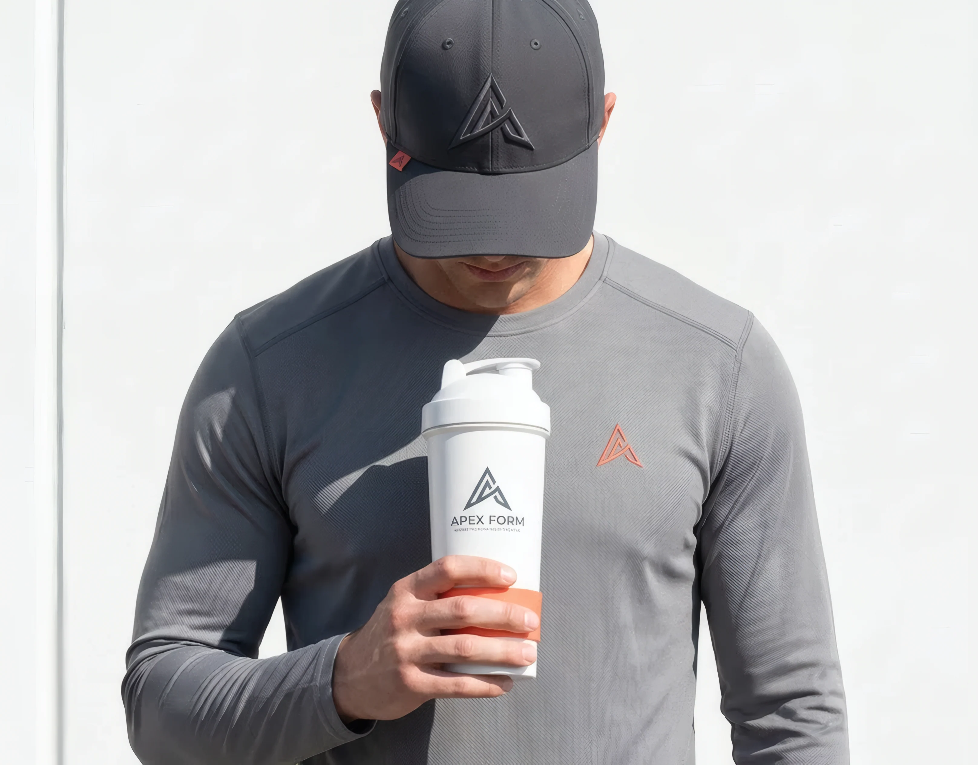 Man in a grey Apex Form long-sleeve top and cap holding an Apex Form shaker